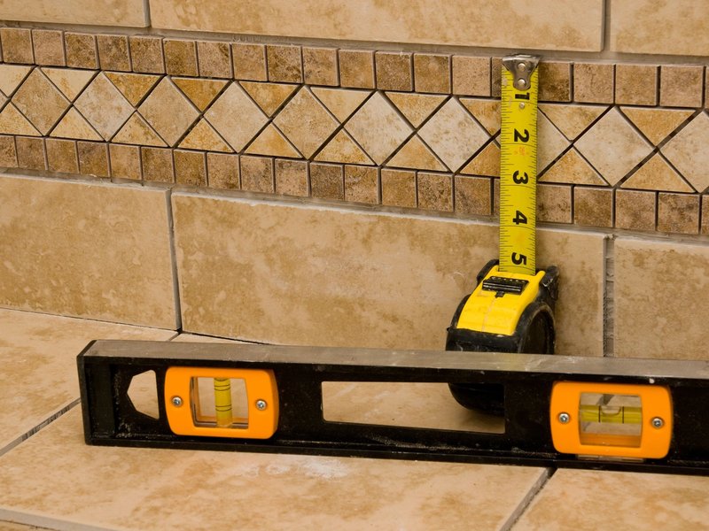 Tape Measure and Level Leaning Up Against A Tiled Wall